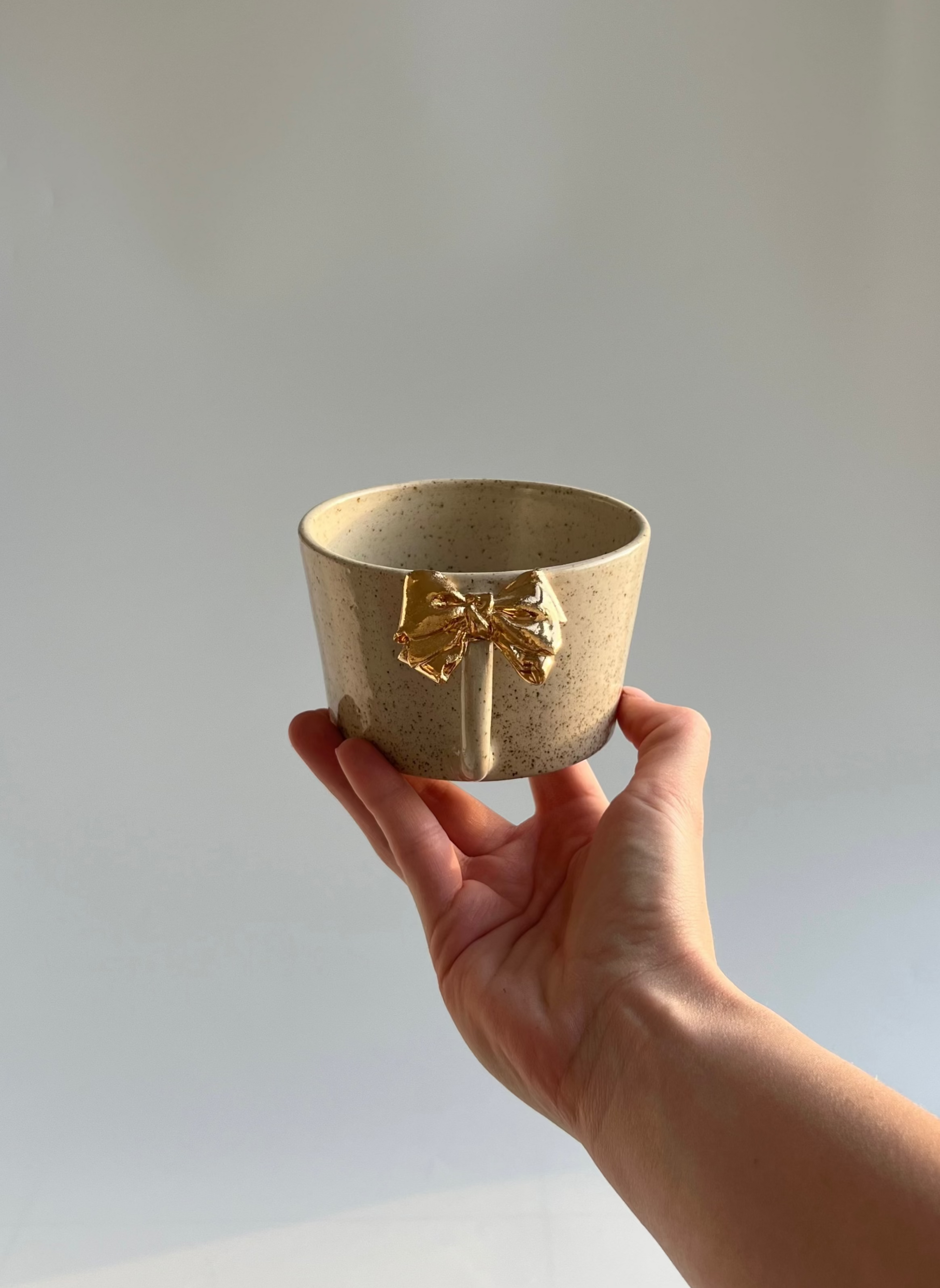 mug with gold bow held by a hand